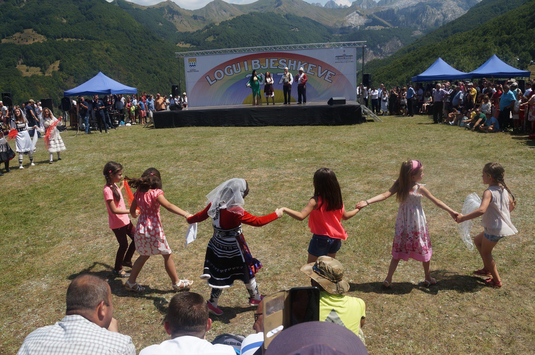 Fëmijë kërcejnë valle dorë për dore në një festë në mal