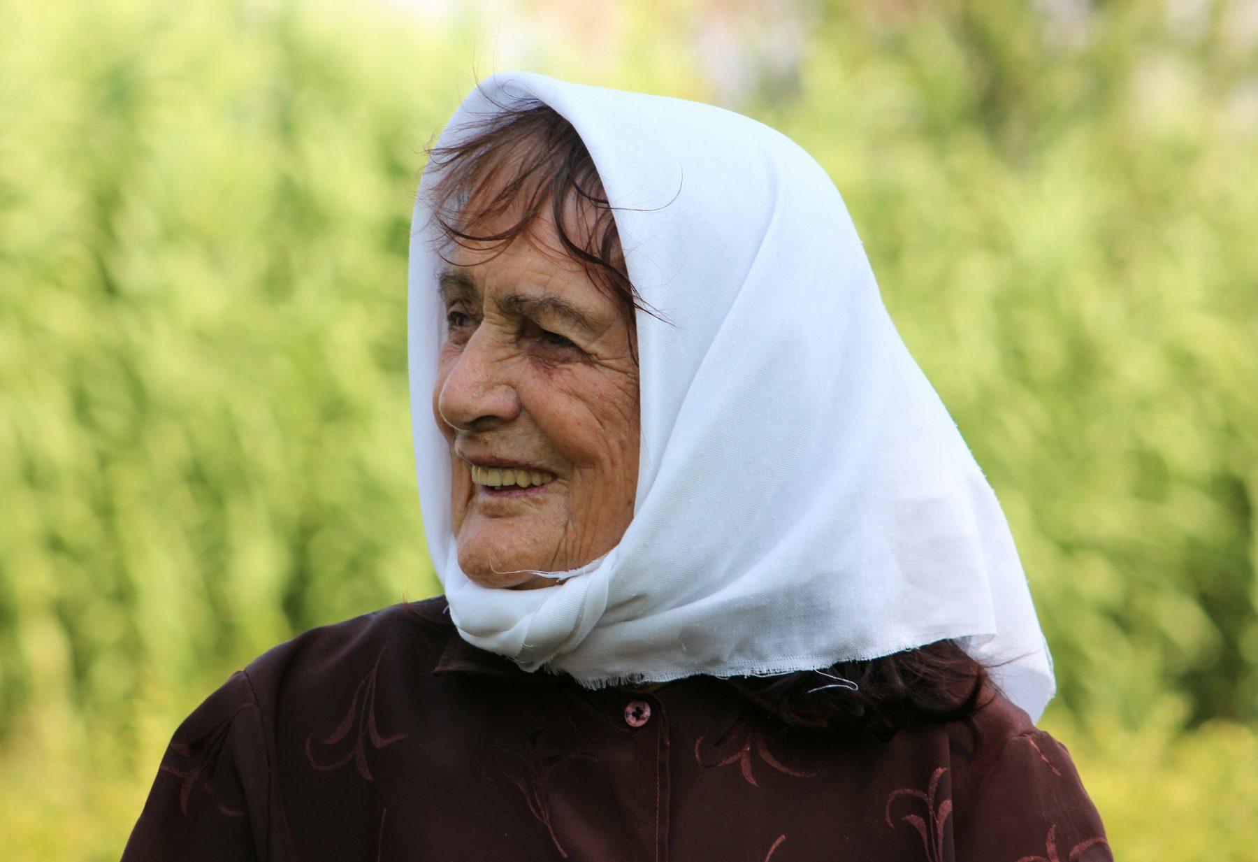 Një gjyshe me shami të bardhë buzëqesh